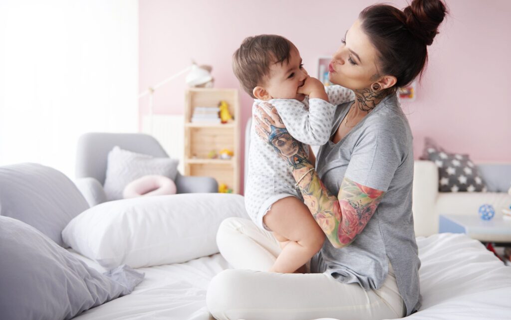 Mladá maminka s batoletem a tetováním.