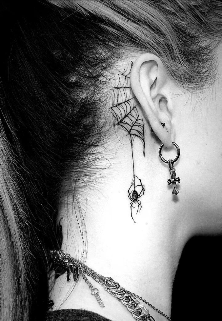 Tetování pavouka a sítě za uchem.
