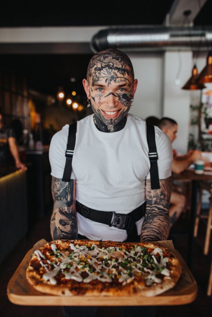 Potetovaný muž s pizzou.